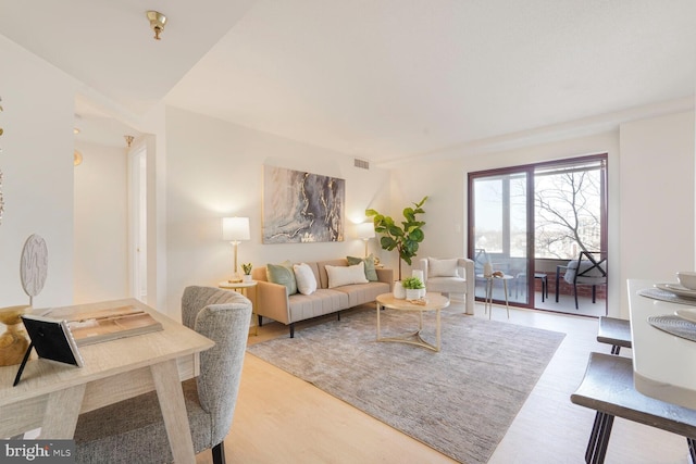 living area featuring visible vents and wood finished floors