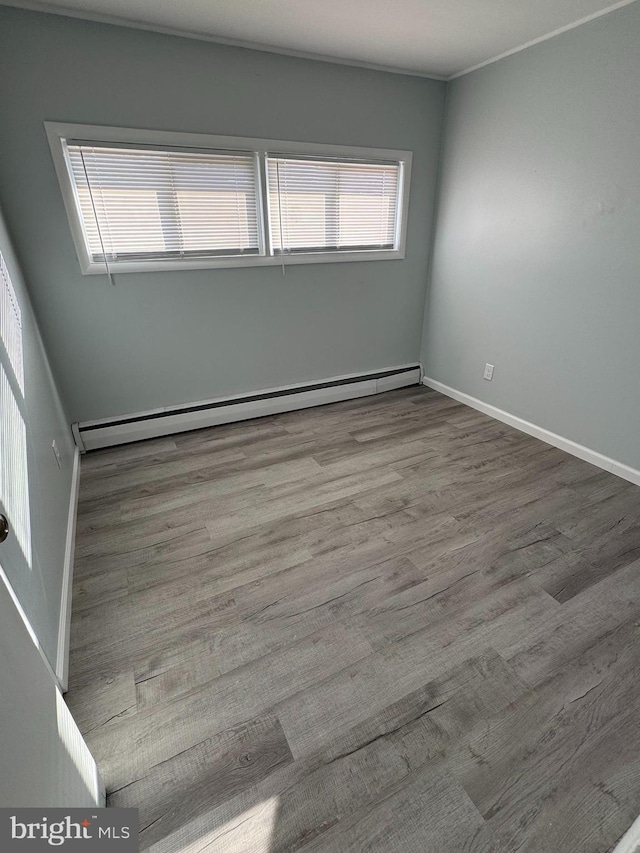 spare room with light wood-type flooring and a baseboard heating unit