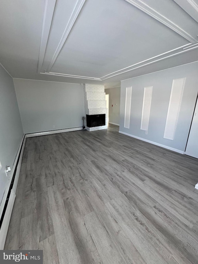 unfurnished living room featuring baseboard heating, hardwood / wood-style floors, and a fireplace