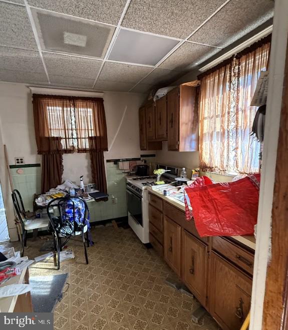 kitchen with a paneled ceiling and white gas range