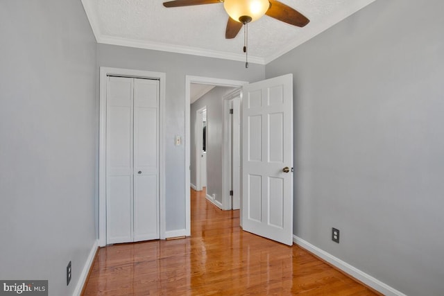 unfurnished bedroom with wood-type flooring, a textured ceiling, a closet, and ceiling fan