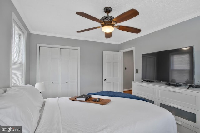 bedroom with ceiling fan, a closet, crown molding, and a textured ceiling