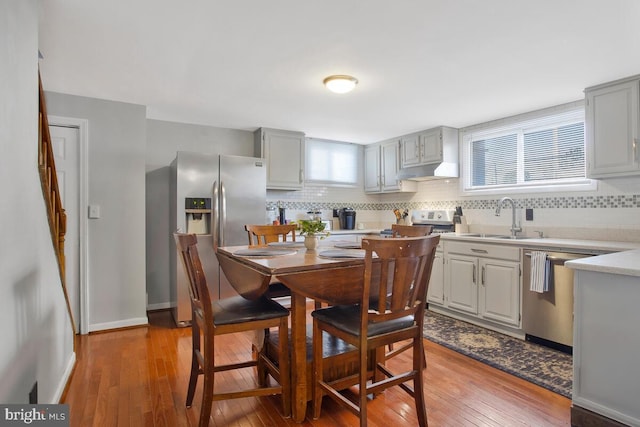 kitchen with gray cabinetry, sink, stainless steel appliances, and wood-type flooring