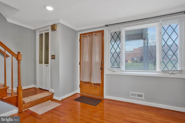 entryway featuring a wealth of natural light, crown molding, and light wood-type flooring