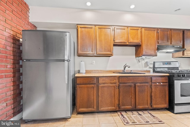 kitchen with brick wall, light tile patterned floors, sink, and appliances with stainless steel finishes