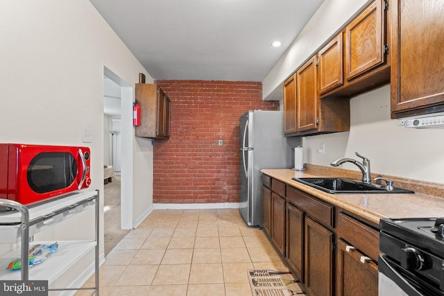 kitchen with sink, black electric range, light tile patterned floors, dishwashing machine, and brick wall