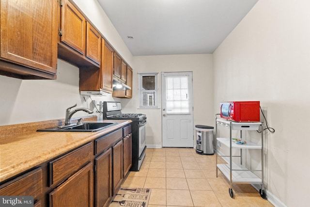 kitchen featuring sink, gas range oven, and light tile patterned flooring