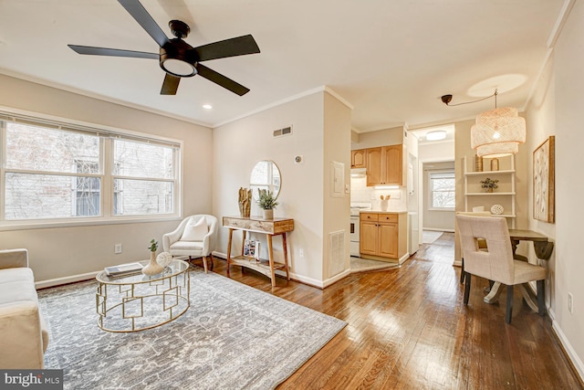 living area featuring crown molding, visible vents, a ceiling fan, wood finished floors, and baseboards