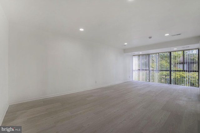 unfurnished room featuring a wall of windows and light hardwood / wood-style floors