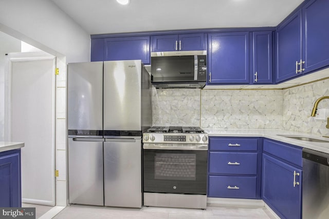 kitchen with decorative backsplash, sink, appliances with stainless steel finishes, and blue cabinetry