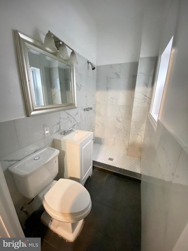 bathroom featuring toilet, tiled shower, decorative backsplash, vanity, and tile walls