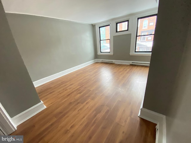 unfurnished room featuring wood-type flooring and a baseboard radiator