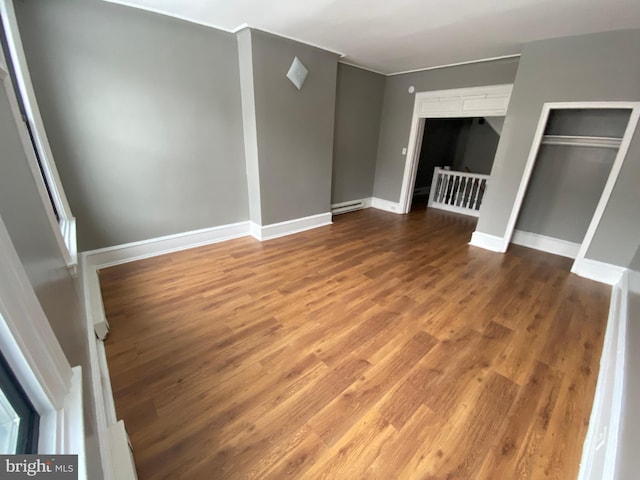 unfurnished bedroom featuring wood-type flooring and baseboard heating