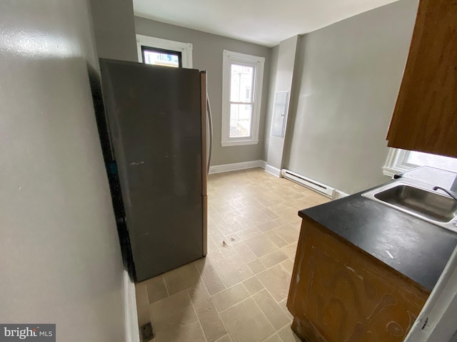 kitchen with stainless steel fridge, sink, and a baseboard heating unit