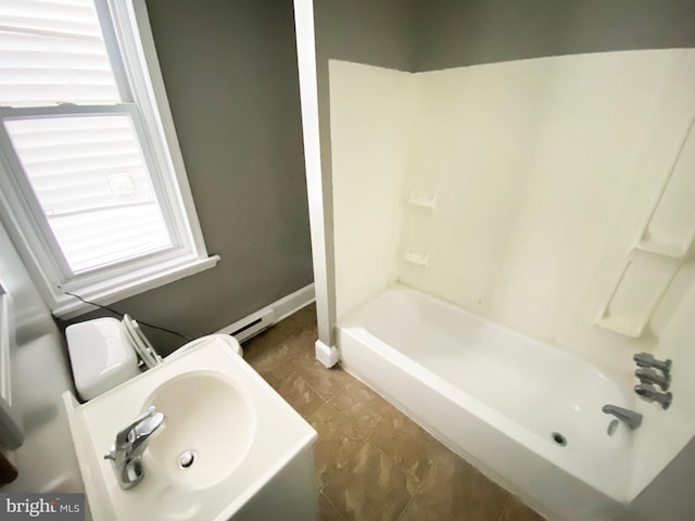 full bathroom featuring toilet, baseboard heating, tub / shower combination, and sink