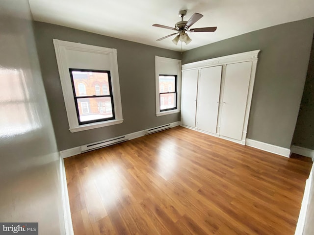 unfurnished bedroom featuring hardwood / wood-style flooring, ceiling fan, a closet, and a baseboard radiator