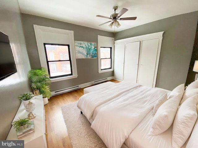 bedroom featuring ceiling fan, a closet, light hardwood / wood-style flooring, and a baseboard radiator