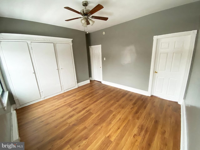 unfurnished bedroom featuring ceiling fan, wood-type flooring, baseboard heating, and a closet