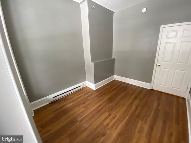 spare room with dark wood-type flooring and a baseboard heating unit