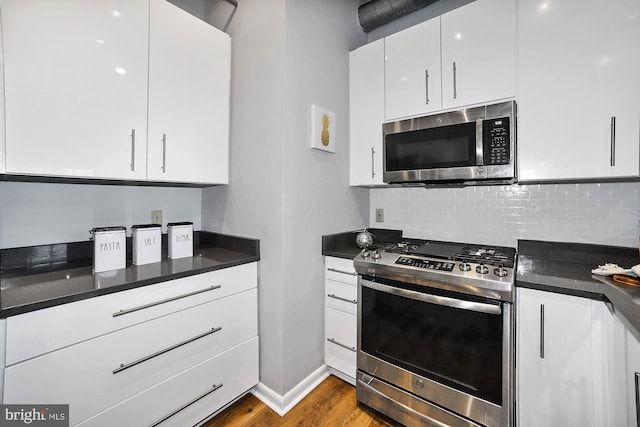 kitchen with backsplash, stainless steel appliances, white cabinetry, and hardwood / wood-style flooring