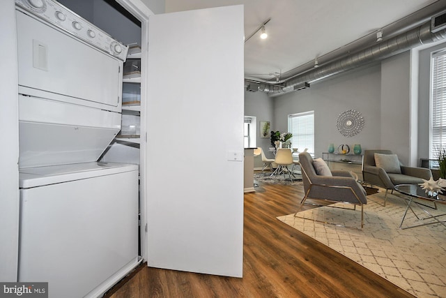 washroom with dark hardwood / wood-style flooring and stacked washing maching and dryer