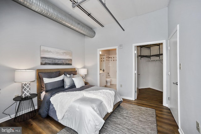 bedroom with a walk in closet, a closet, ensuite bath, and dark wood-type flooring