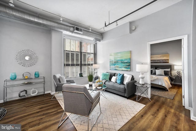 living room with dark hardwood / wood-style flooring and track lighting