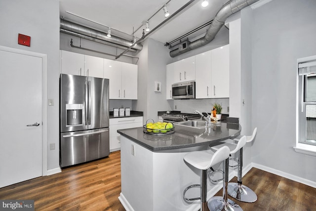 kitchen with kitchen peninsula, white cabinetry, sink, and appliances with stainless steel finishes