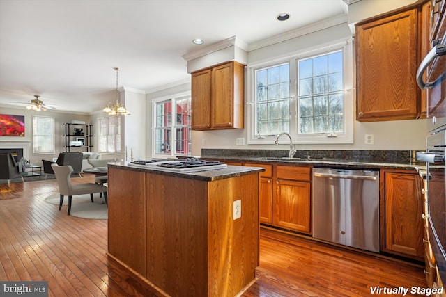 kitchen with sink, dark wood-type flooring, a kitchen island, ceiling fan with notable chandelier, and appliances with stainless steel finishes