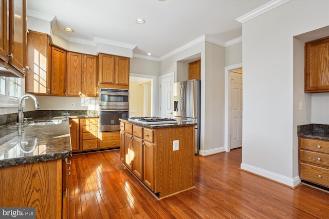 kitchen with a center island, stainless steel appliances, ornamental molding, and dark stone countertops