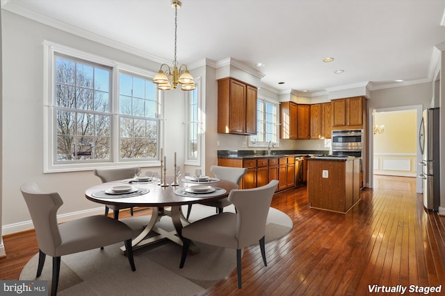 kitchen with dark hardwood / wood-style flooring, stainless steel appliances, decorative light fixtures, an inviting chandelier, and a center island