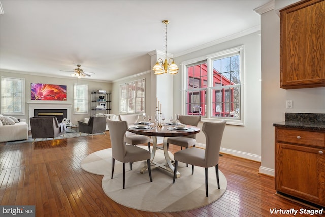 dining area with wood-type flooring, ceiling fan with notable chandelier, and ornamental molding