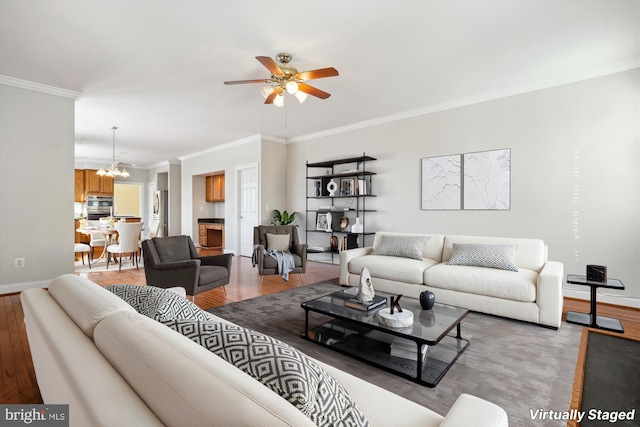 living room featuring ceiling fan with notable chandelier, light wood-type flooring, and ornamental molding