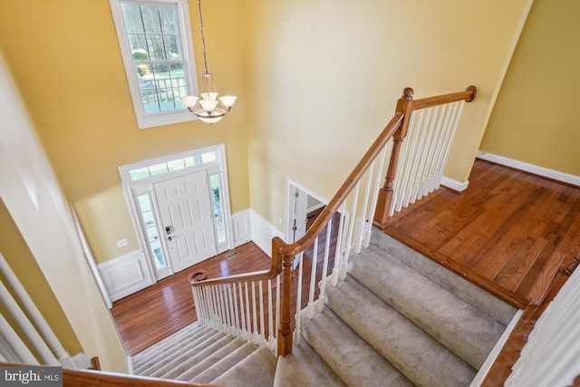 foyer with hardwood / wood-style flooring, a high ceiling, and a chandelier