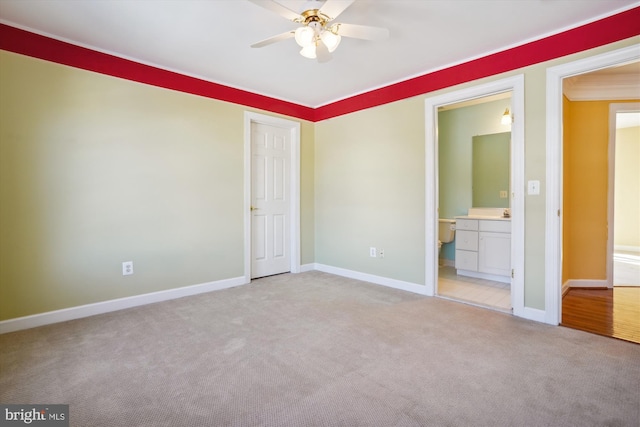 unfurnished bedroom featuring ensuite bathroom, ceiling fan, light colored carpet, and crown molding