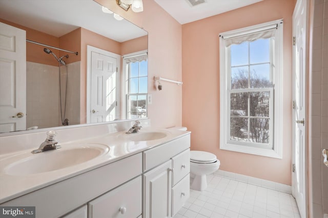 bathroom with vanity, a healthy amount of sunlight, toilet, and a shower