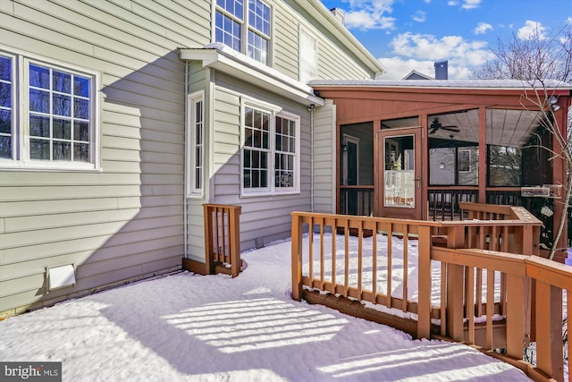 snow covered deck featuring a sunroom