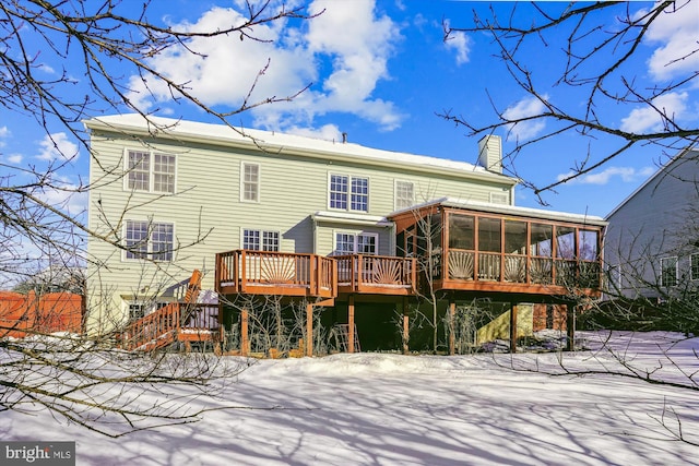 snow covered house featuring a deck and a sunroom