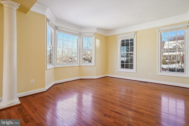 unfurnished room featuring wood-type flooring, decorative columns, and ornamental molding