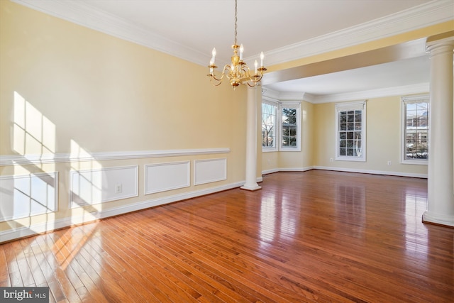 interior space featuring wood-type flooring, an inviting chandelier, crown molding, and ornate columns