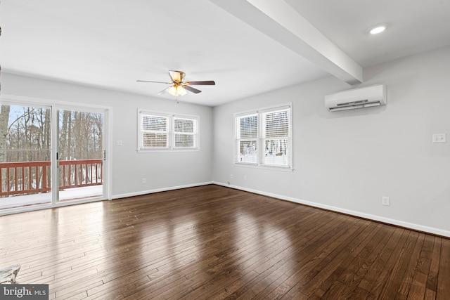 empty room featuring beamed ceiling, a healthy amount of sunlight, dark wood-type flooring, and a wall unit AC