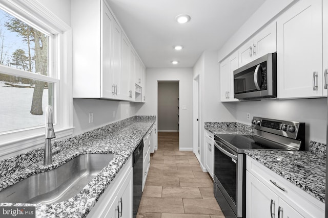 kitchen featuring sink, built in desk, white cabinets, and appliances with stainless steel finishes