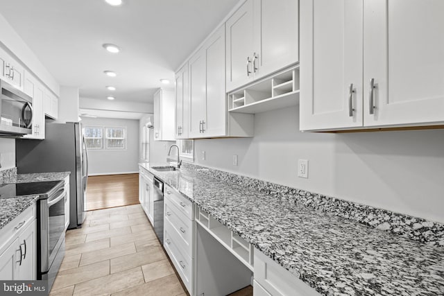 kitchen with sink, light stone counters, white cabinetry, and stainless steel appliances