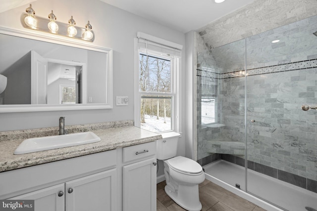 bathroom featuring a wealth of natural light, toilet, walk in shower, and vanity