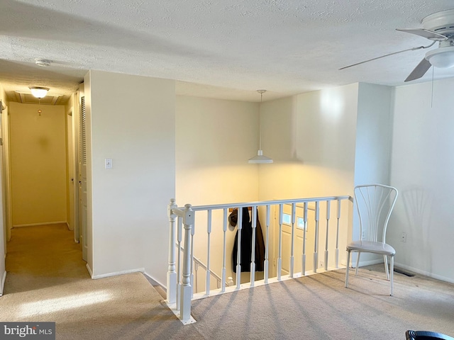 hallway featuring a textured ceiling and light colored carpet