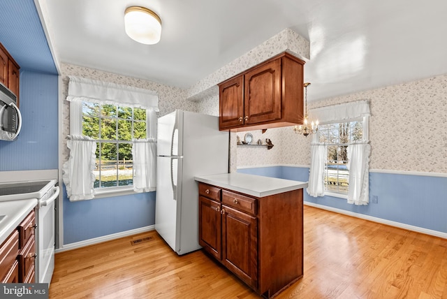 kitchen with white appliances, light wood-type flooring, and hanging light fixtures