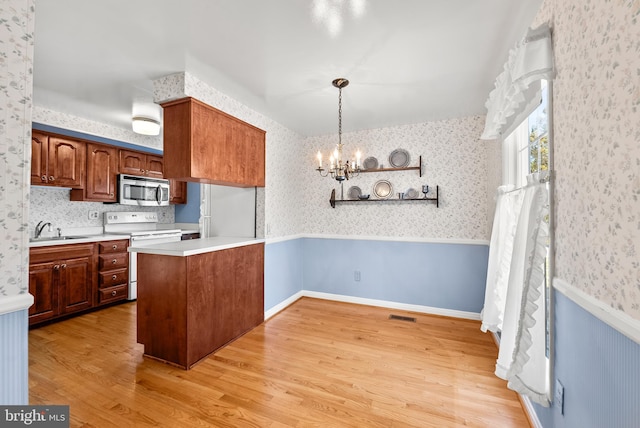 kitchen featuring sink, decorative light fixtures, light wood-type flooring, kitchen peninsula, and electric range