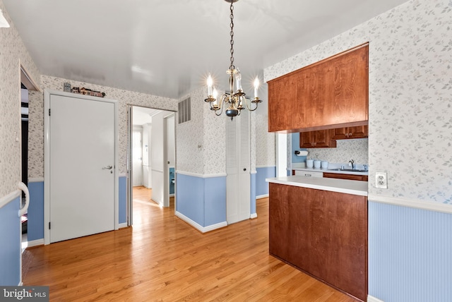 kitchen featuring sink, a chandelier, light wood-type flooring, and pendant lighting