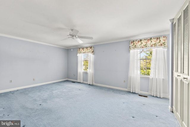 unfurnished room featuring ceiling fan, light colored carpet, and crown molding