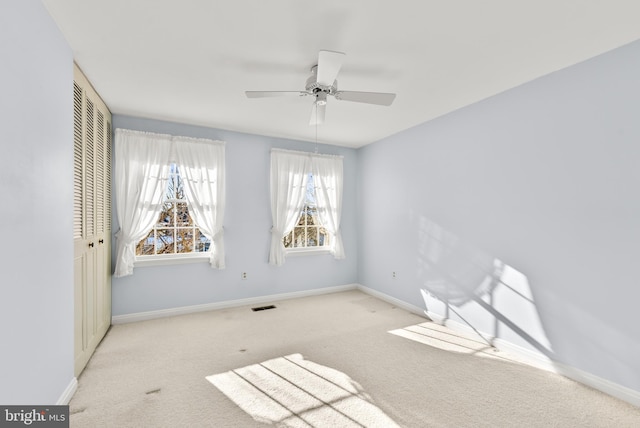 carpeted spare room featuring ceiling fan